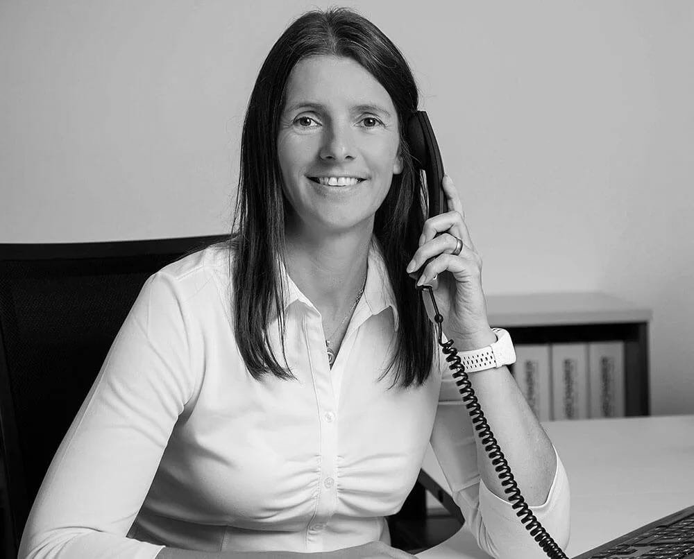 Mitarbeiterin am Telefon im Büro, schwarz-weiß